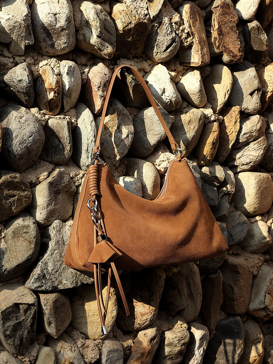Brown nubuck leather tote displayed against rustic stone wall