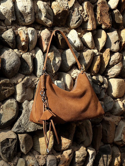 Brown nubuck leather tote displayed against rustic stone wall