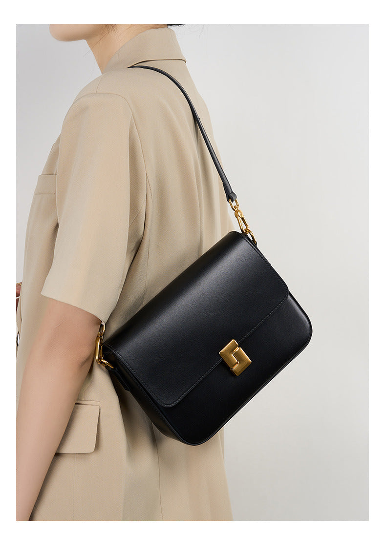 Black cowhide crossbody bag worn crossbody showing back angle and strap