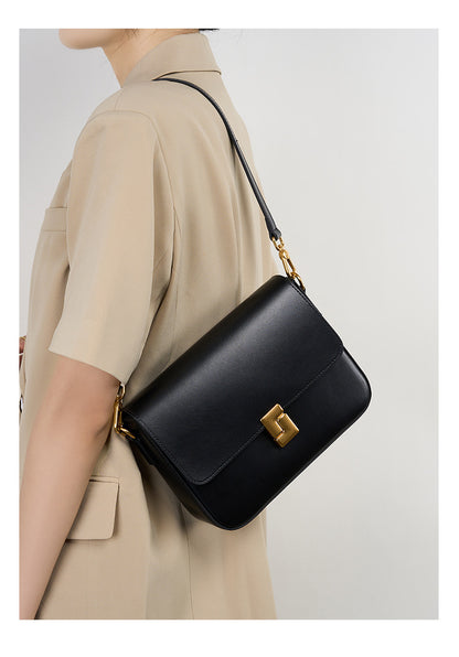 Black cowhide crossbody bag worn crossbody showing back angle and strap