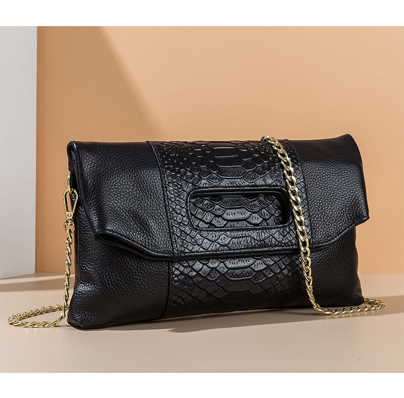 Black croc-embossed clutch displayed at an angle