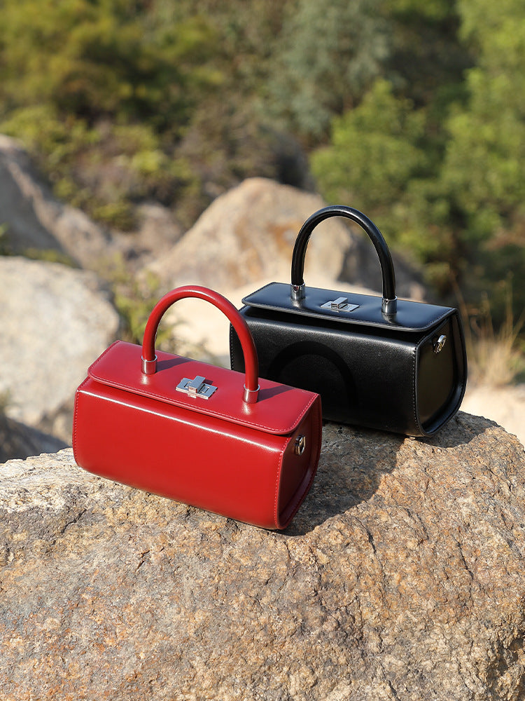 Red and black box handbags displayed together on a stone surface