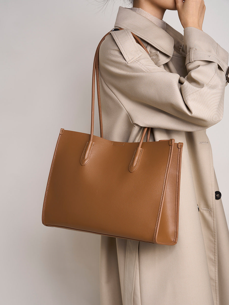 Golden brown tote bag styled with a beige trench coat for everyday wear