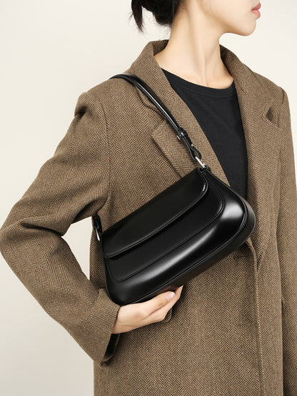 Close-up of the black leather baguette bag's front flap and stitching