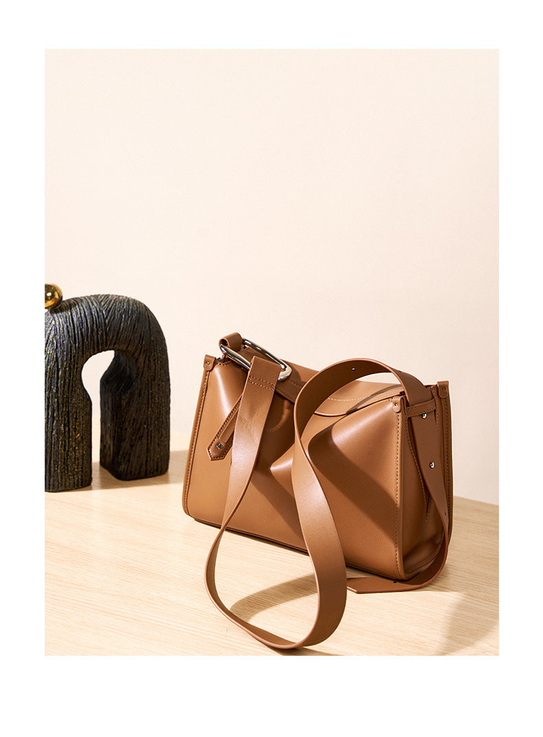 Brown pillow bag styled with decorative wooden sculpture