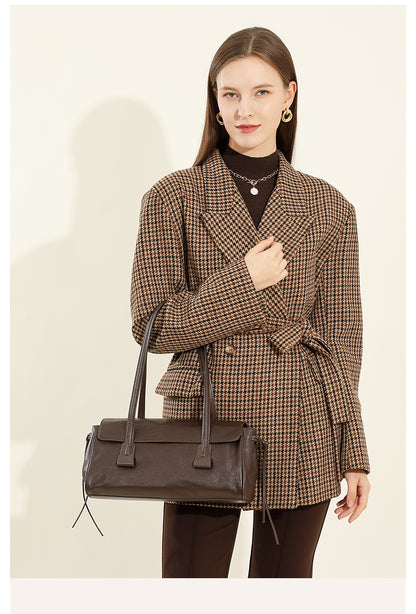 Model in houndstooth coat carrying dark brown cowhide leather shoulder bag by side