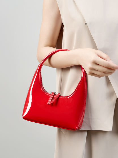 Model carrying red patent mini hobo bag by the top handle