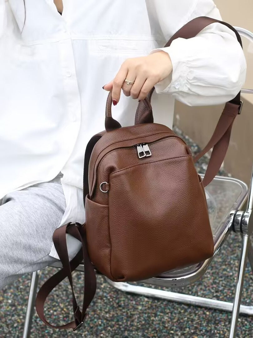 Close view of the brown backpack's front pocket and zip closure