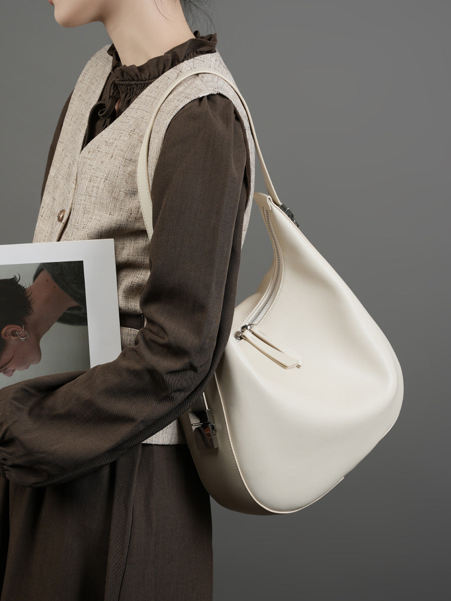 Model in brown blouse and tweed vest carrying the cream white cowhide leather crescent hobo bag on the shoulder
