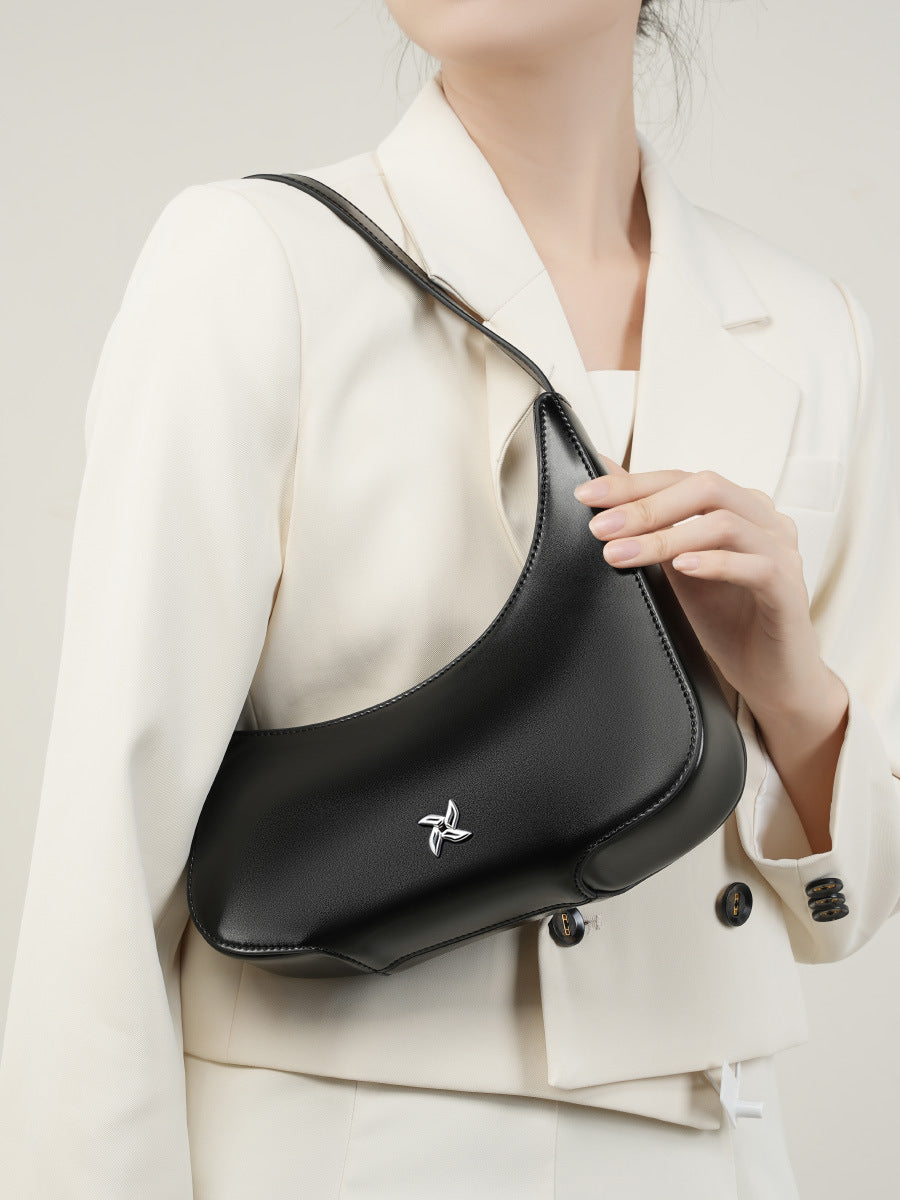 Black crescent bag held by hand showing smooth leather texture