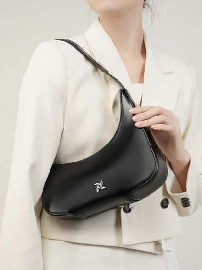 Black crescent bag held by hand showing smooth leather texture