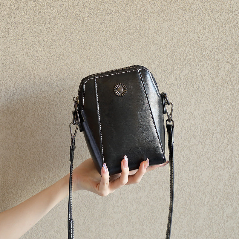 Black cowhide leather mini crossbody phone bag held in hand