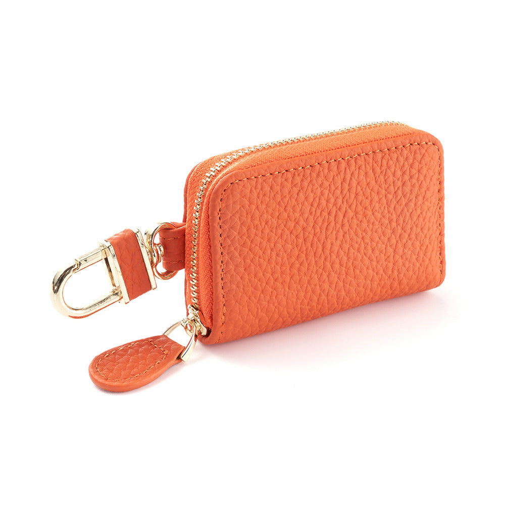 Orange cowhide leather key case pouch with single zipper and gold-tone rotating clip on white background