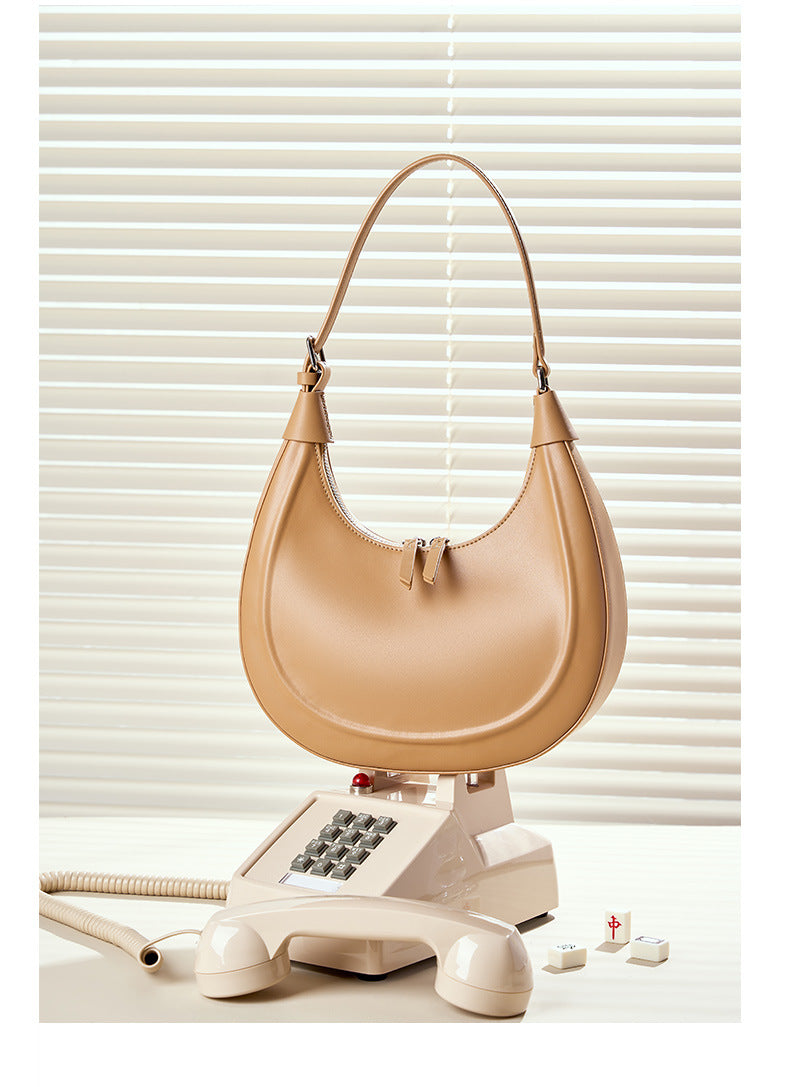 Milk tea colored crescent cowhide bag styled on a vintage telephone