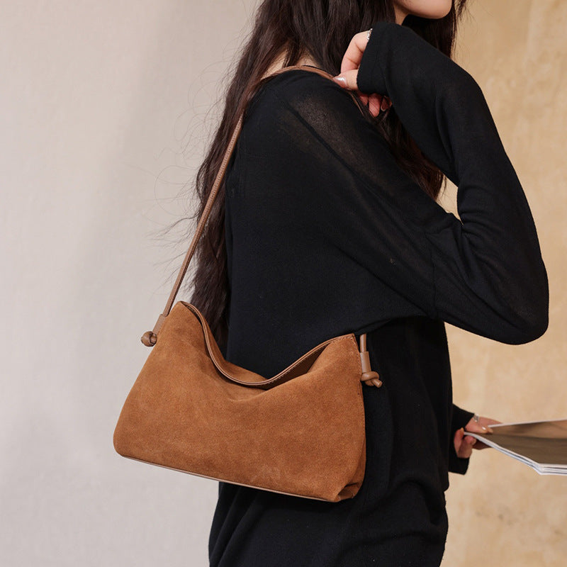 Model wearing the brown leather bag over one shoulder