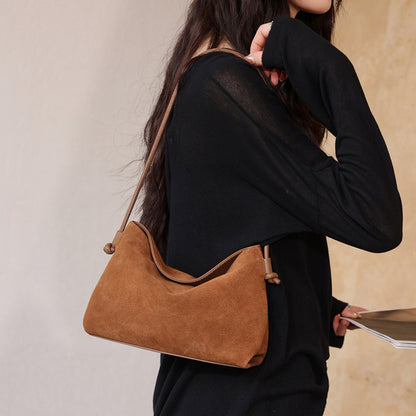 Model wearing the brown leather bag over one shoulder