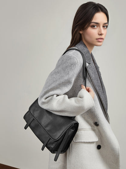 Model wearing black leather messenger crossbody bag with a light gray wool coat