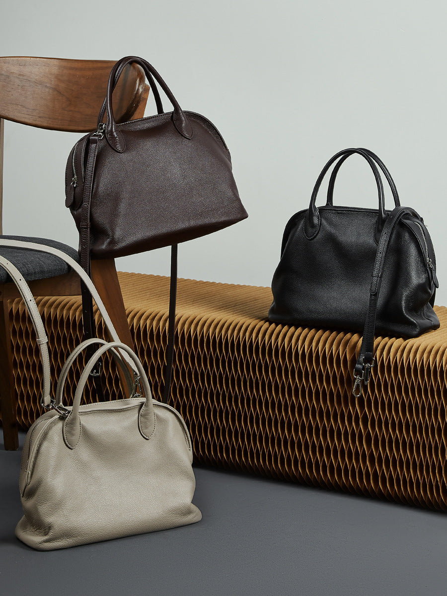 Light gray, coffee brown, and black pebbled cowhide bowling totes styled together in a lifestyle group shot