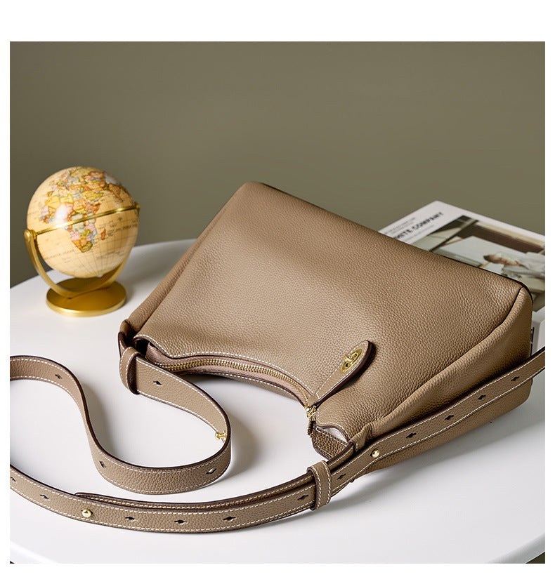Off-white leather shoulder bag laid flat showing adjustable strap and turn-lock