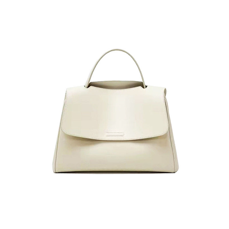 White cowhide leather top-handle bag with flap closure on white background