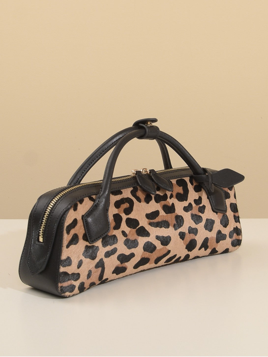 Three-quarter view showing leopard-print panel, black trim, and zip top