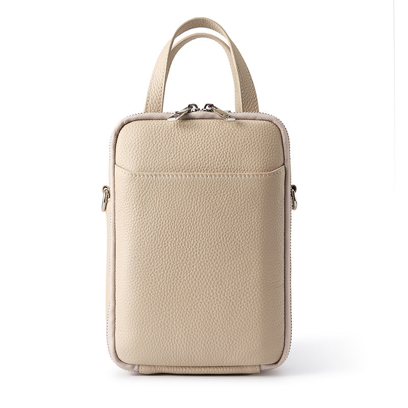 Off-white top-grain cowhide vertical phone crossbody bag with twin top handles and front slip pocket on white background