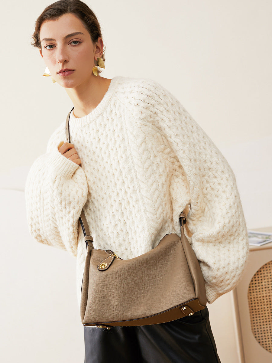 Model wearing dark gray leather shoulder bag crossbody style with cream sweater
