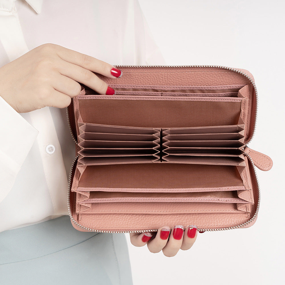 Hands holding an open pink accordion wallet with organized card slots