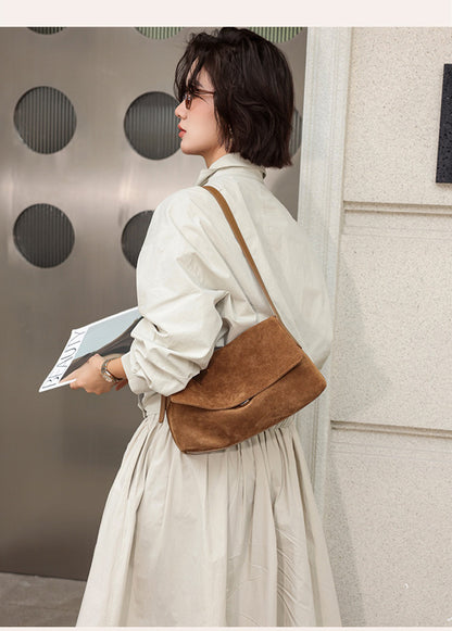 Caramel leather flap bag held by a model in a light outfit