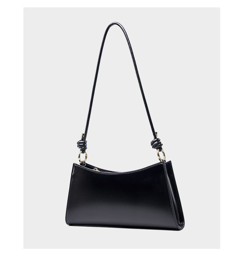 Black cowhide leather shoulder bag standing upright against a light gray backdrop