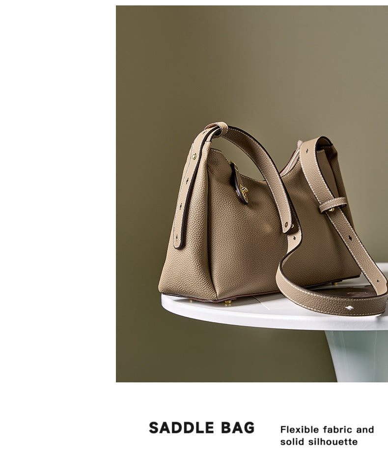 Side view of light gray leather shoulder bag with adjustable strap on table