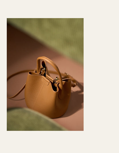 Biscuit bucket bag photographed on green textured surface with warm lighting