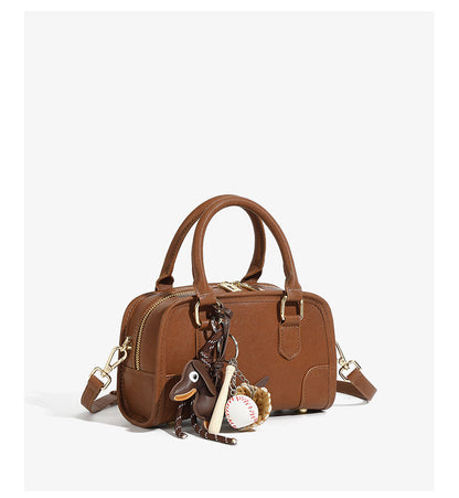 Brown mini bowling bag with detachable crossbody strap and charms