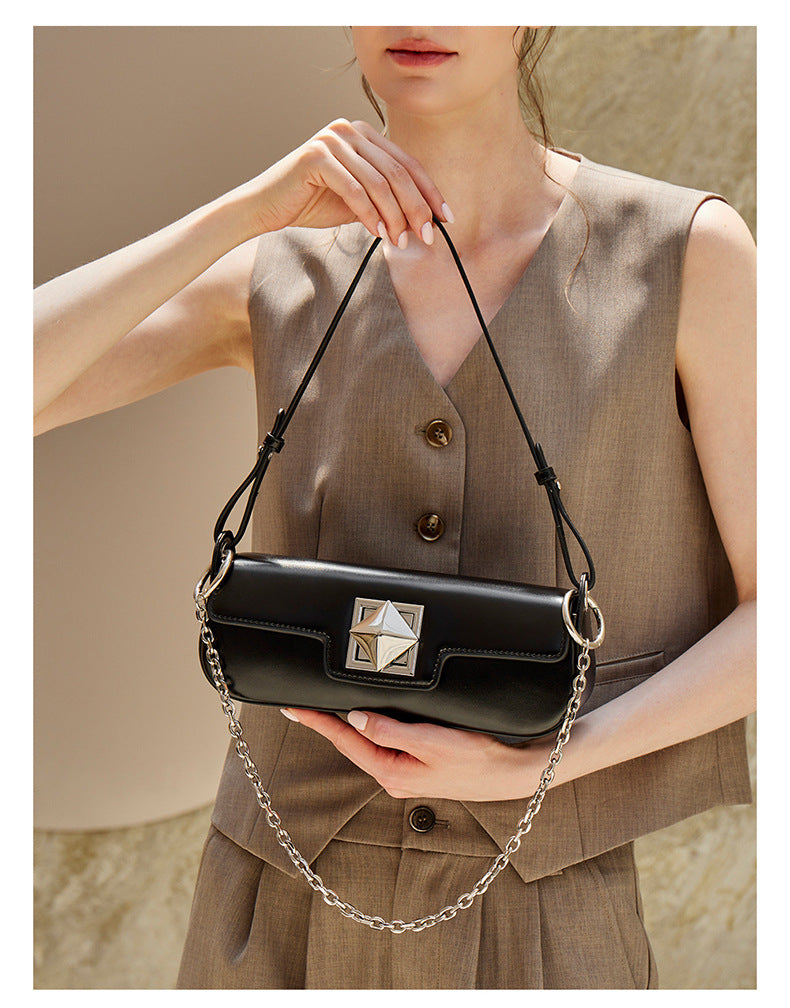 Model holding black leather baguette shoulder bag with chain strap