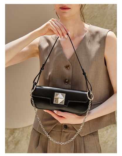 Model holding black leather baguette shoulder bag with chain strap