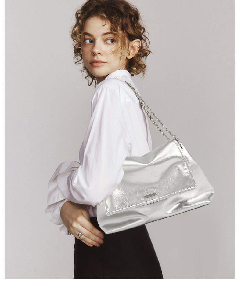 Side profile of silver chain shoulder bag worn with white shirt and black trousers