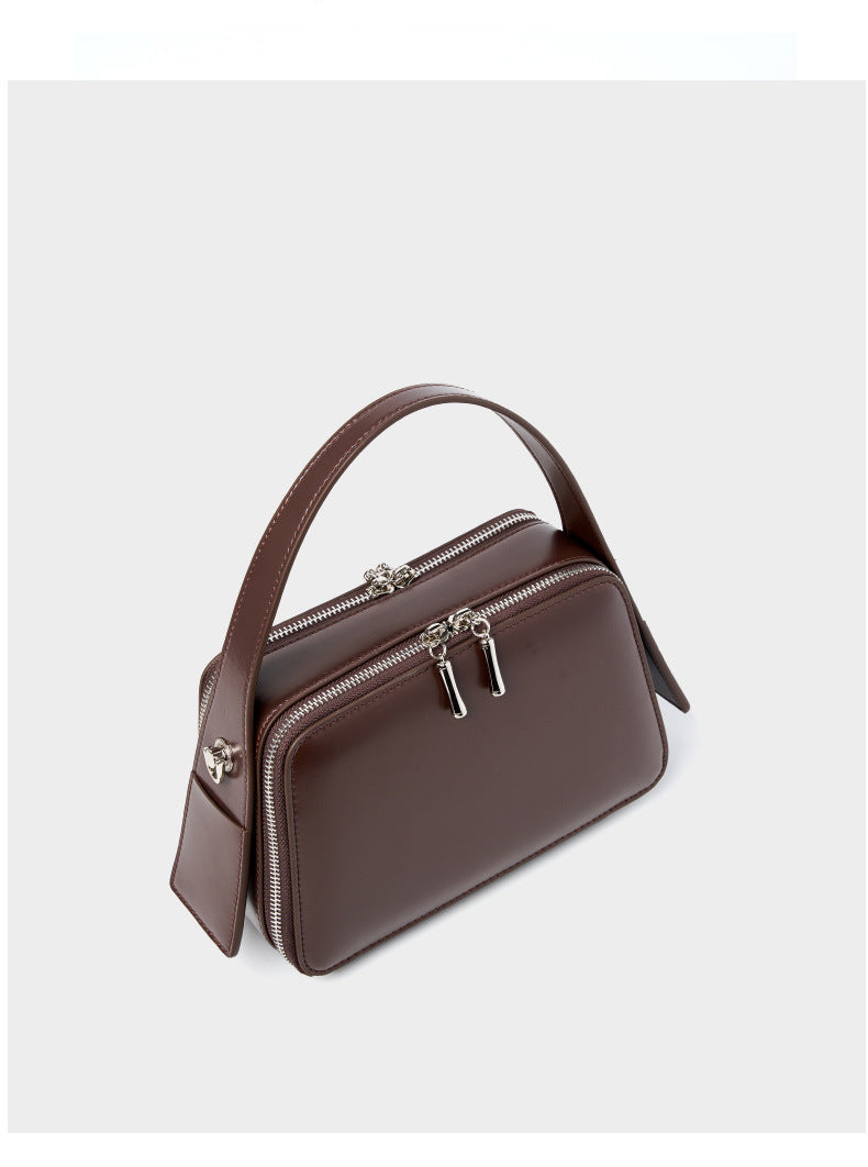 Angled view of the coffee brown leather crossbody bag showing the dual-zip top