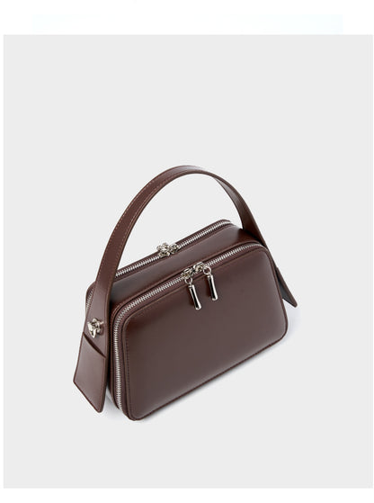Angled view of the coffee brown leather crossbody bag showing the dual-zip top