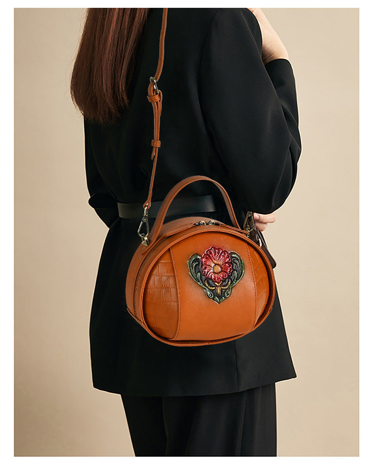 Brown floral leather bag worn crossbody with its detachable shoulder strap