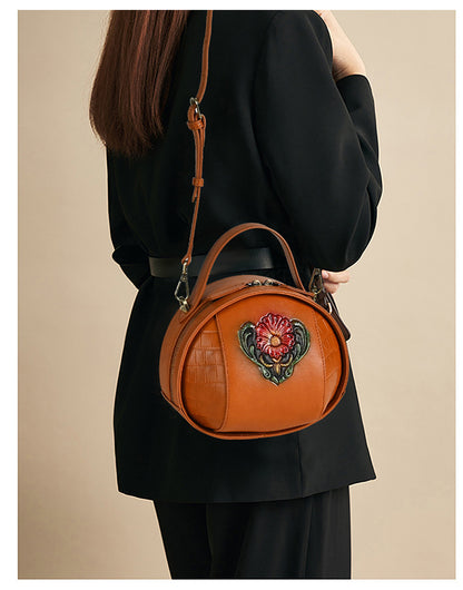 Brown floral leather bag worn crossbody with its detachable shoulder strap