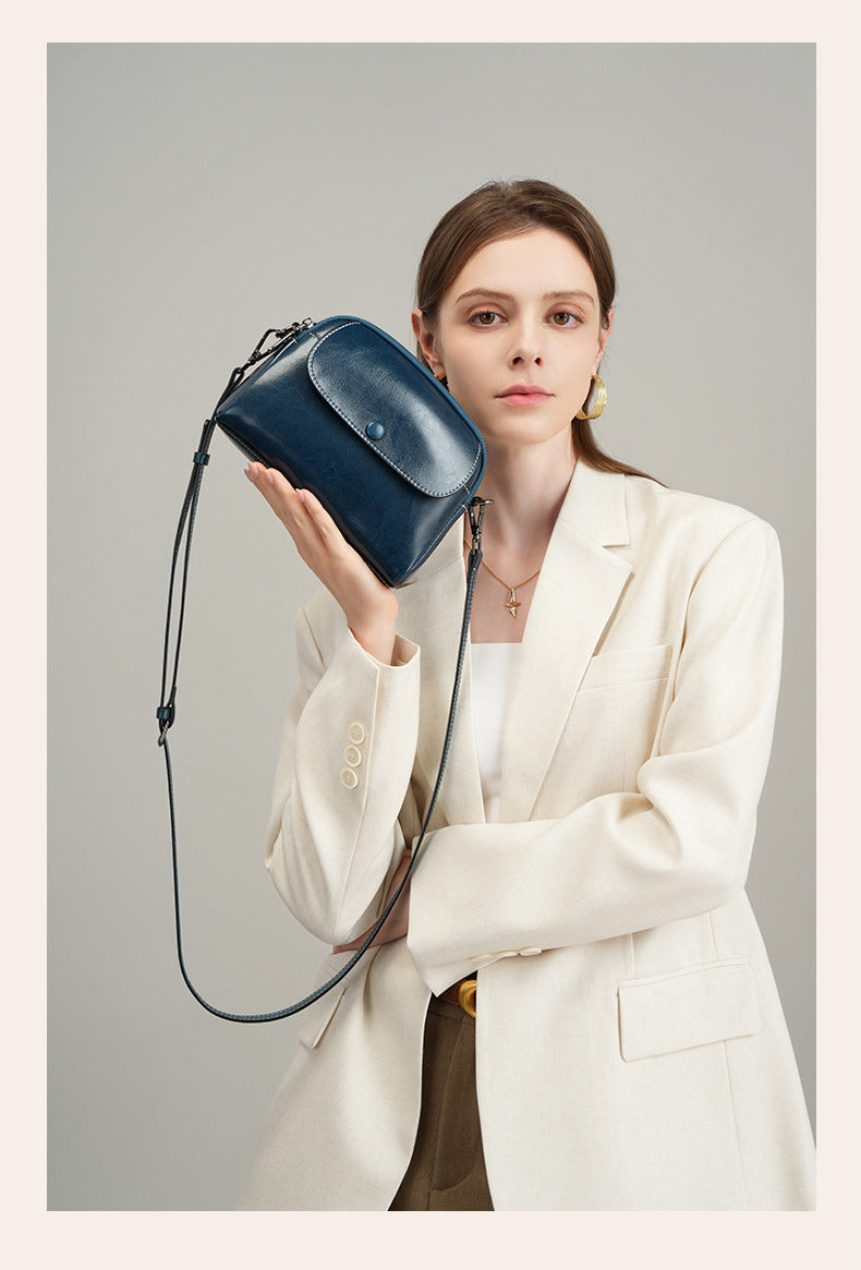 Model holding peacock blue oil-waxed leather crossbody bag