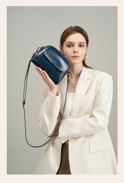 Model holding peacock blue oil-waxed leather crossbody bag