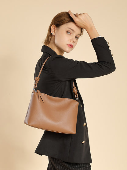 Side view of model carrying caramel leather pillow tote over her shoulder