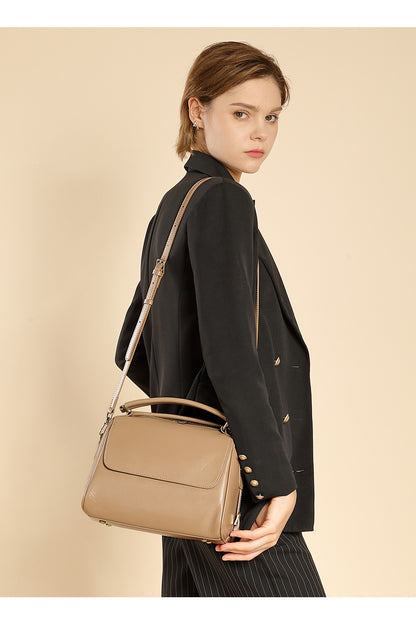Apricot leather Boston bag worn crossbody by model in black blazer