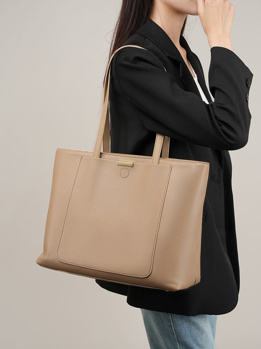 Side lifestyle view of apricot pebbled leather tote carried under the arm