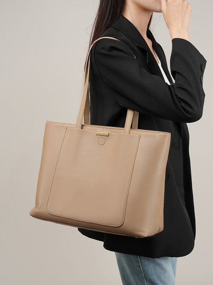 Side lifestyle view of apricot pebbled leather tote carried under the arm