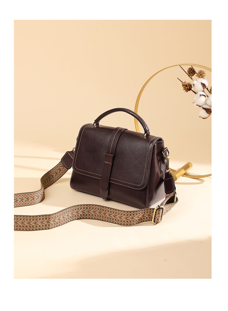 Wine brown leather Boston bag styled with wide woven strap and decorative dried florals
