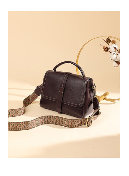 Wine brown leather Boston bag styled with wide woven strap and decorative dried florals