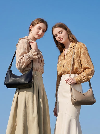 Two models wearing leather hobo bags outdoors