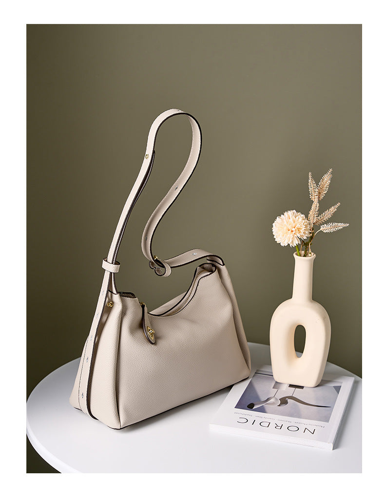 Off-white leather shoulder bag styled with vase and book on side table